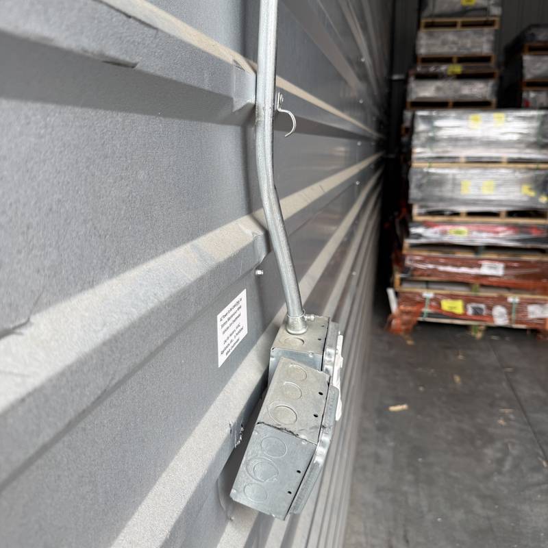 Surface-mounted conduit and outlet boxes on a metal building wall