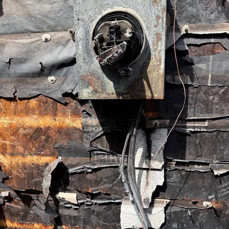 Fire-damaged electrical meter socket on the side of a house
