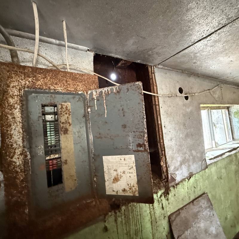 Rusted, outdated electrical panel in an older home before rewiring